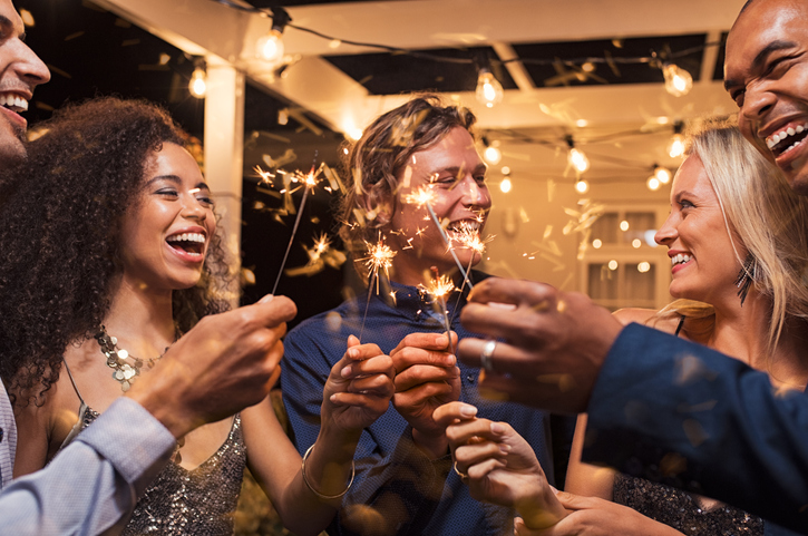An image of friends celebrating together by holding up sparklers in the air as if in a toast to one another.