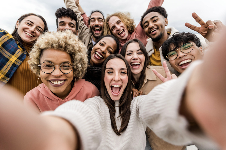 A group of multiracial friends taking a wide selfie together.