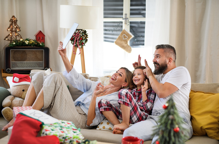A family taking a selfie together at Christmas while lounging on the couch.