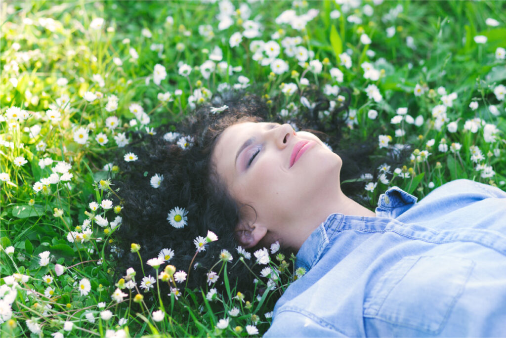 a woman laying in grass and flowers.