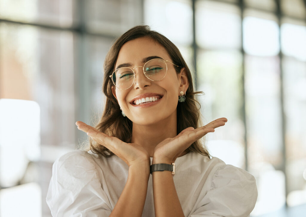 Happy woman with glasses posing with her hands under her face showing her smile.