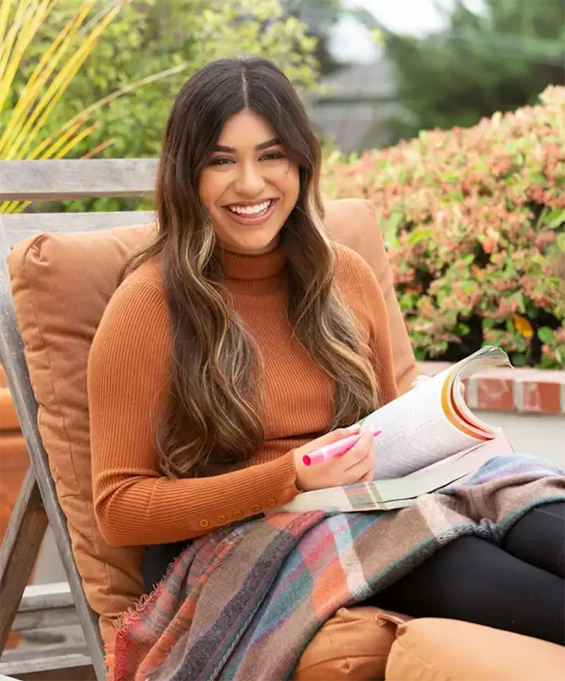 Smiling women sitting down reading and writing