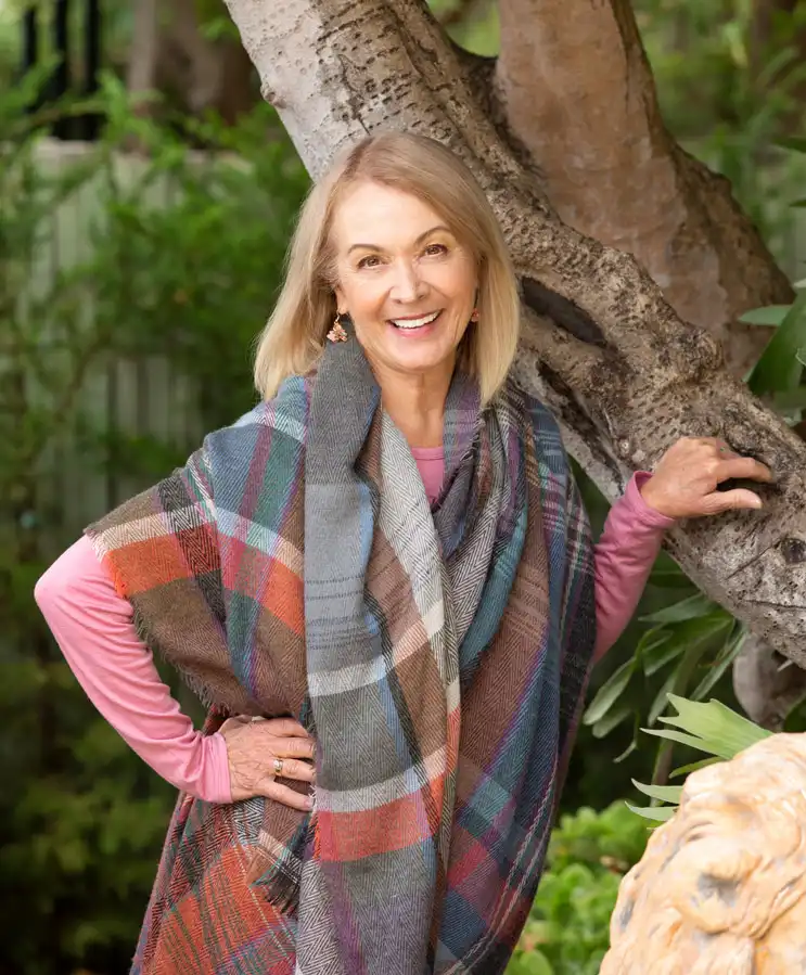 Woman leaning next to a tree smiling