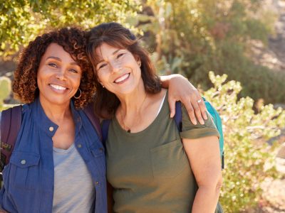 Portrait Of Two Senior Female Friends Hiking Along Trail In Countryside Together