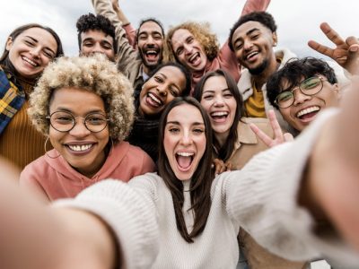 A group of multiracial friends taking a wide selfie together.