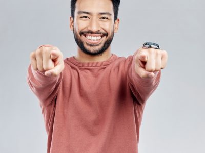 Pointing, selection and smile with portrait of man in studio for thank you, motivation and amazing.