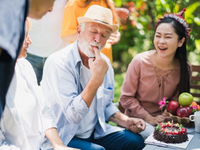 A happy, smiling family having lunch together outside in the sunlight.