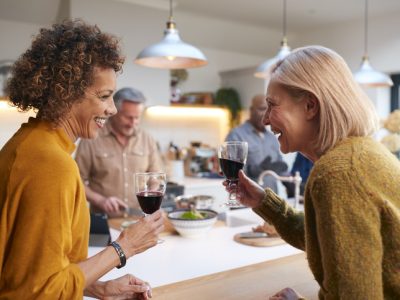 A group of friends preparing a meal together in someone's home kitchen, laughing together.