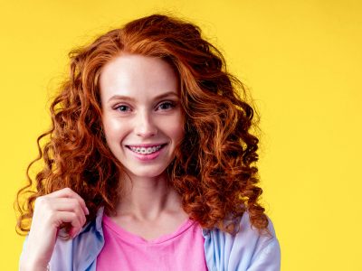 A redheaded woman smiling brightly at the camera with photoshopped-on braces.