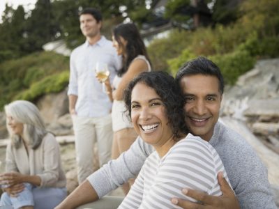 A smiling couple sitting down on the beach.