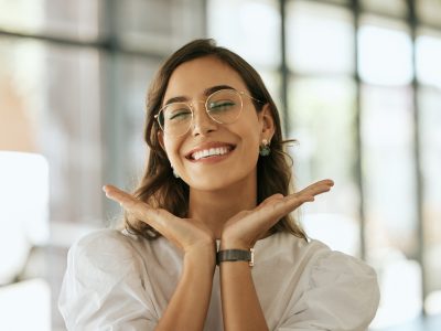 Happy woman with glasses posing with her hands under her face showing her smile.