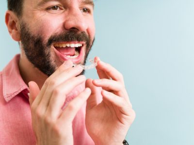 A man opening his mouth wide to insert the upper row of his Invisalign Invisaligners.