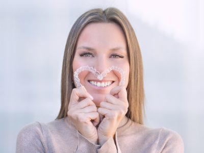 Woman with bright smile holding her upper and lower Invisaligners.