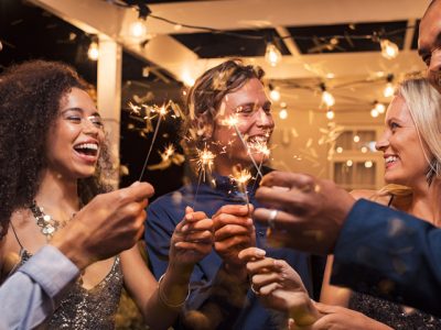 An image of friends celebrating together by holding up sparklers in the air as if in a toast to one another.