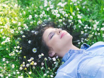 a woman laying in grass and flowers.