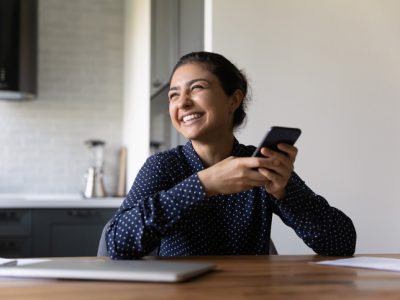 Overjoyed young indian woman holding cellphone laughing on internet joke.